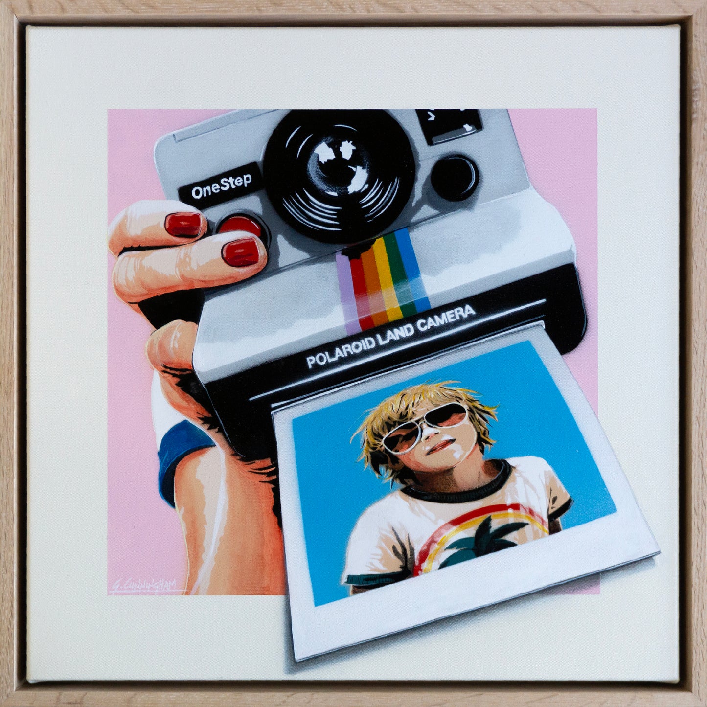 Framed artwork of a Polaroid camera and a person holding it with a colorful photo attached.