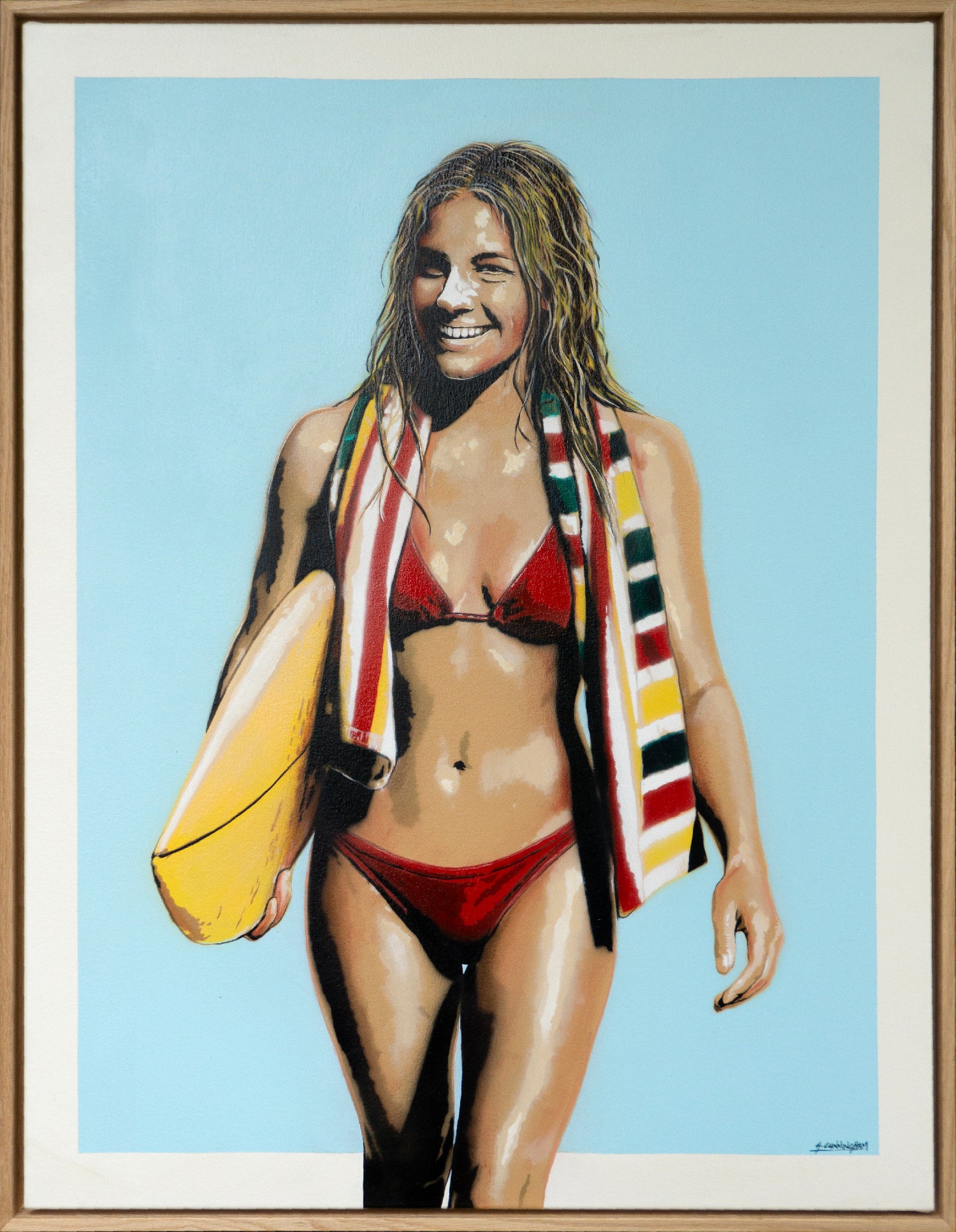Woman in red bikini holding a yellow surfboard with a towel draped over her shoulder against a blue sky.